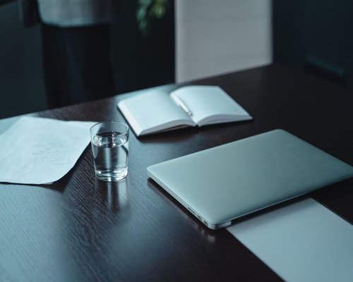 Ergonomic desk setup with laptop, water glass, and notebook
